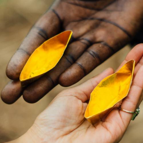 Hands of ARCC chairman Abann Yor and artist Tiffany Singh with golden boats. Image credit Ben Journee